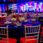 Awards dinner with a patriotic stage and round tables with red chairs