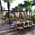 Cabana dining under palm trees with draped pergolas