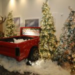 Red pickup truck bed with flocked Christmas trees and faux snow