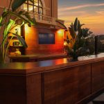 Wood-paneled bar with tropical plants under warm lighting