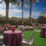 Lawn seating with round tables, clear chairs and a fire pit