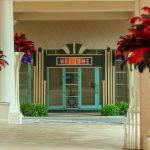 Art deco welcome entrance with red flowers in tall urns