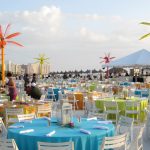 Beachfront tables in bright linens with colorful inflatable palm trees