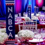 Association dinner with patriotic stage lighting and white floral centerpieces