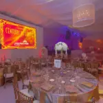 Draped banquet tent with round tables and large video screens