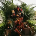 Costumed pirate figure posed among palms and crates