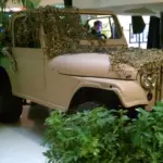 Safari-style Jeep with camouflage netting and foliage