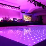 Magenta LED dance floor under pink uplighting with a stage