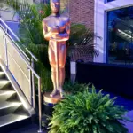 Tall gold award statue beside a staircase with ferns