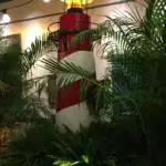 Decorative red and white lighthouse prop framed by palms
