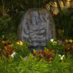 Low-lying ferns and flowers around a carved stone idol