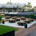 Round dining tables on a white floor set up on a baseball field