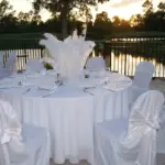 Lakeside terrace with white-draped round tables and feather centerpieces