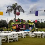 Outdoor lawn party with paper lanterns, food trucks and white round tables