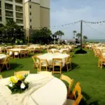 Lawn dining with round tables, yellow florals and string lights