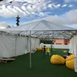 White event tent with string lights, turf and yellow bean bag seating